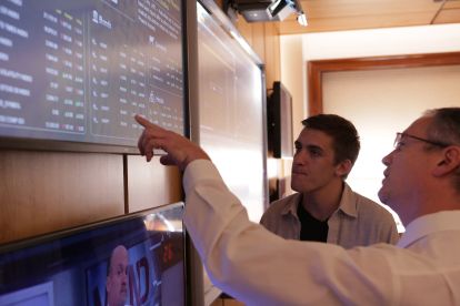 Student and faculty member looking at a stock ticker in a financial markets classroom