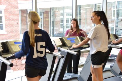 teacher showing student a treadmill for a physical education class