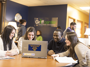 students sitting around a laptop together at a table in a student center